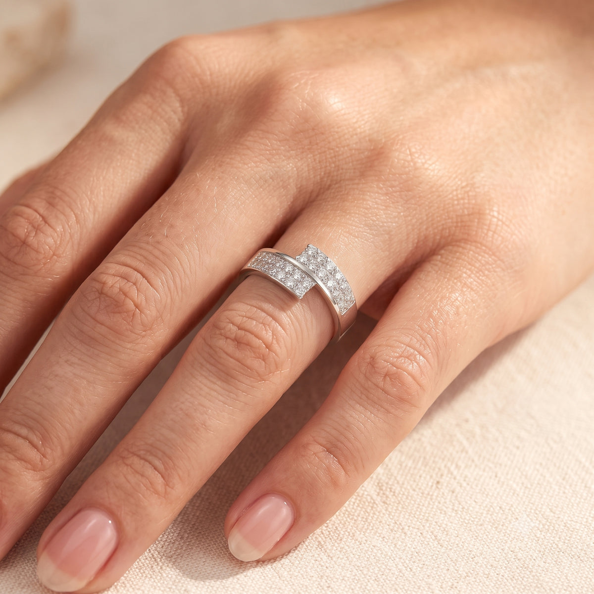 Top view of the sterling silver Eldria bypass ring with round simulated diamonds worn on a woman's finger.