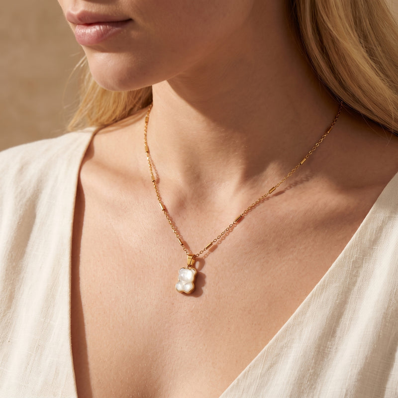 Model wearing the gold-tone bear pendant necklace with a white top, showing how it sits on the neckline.