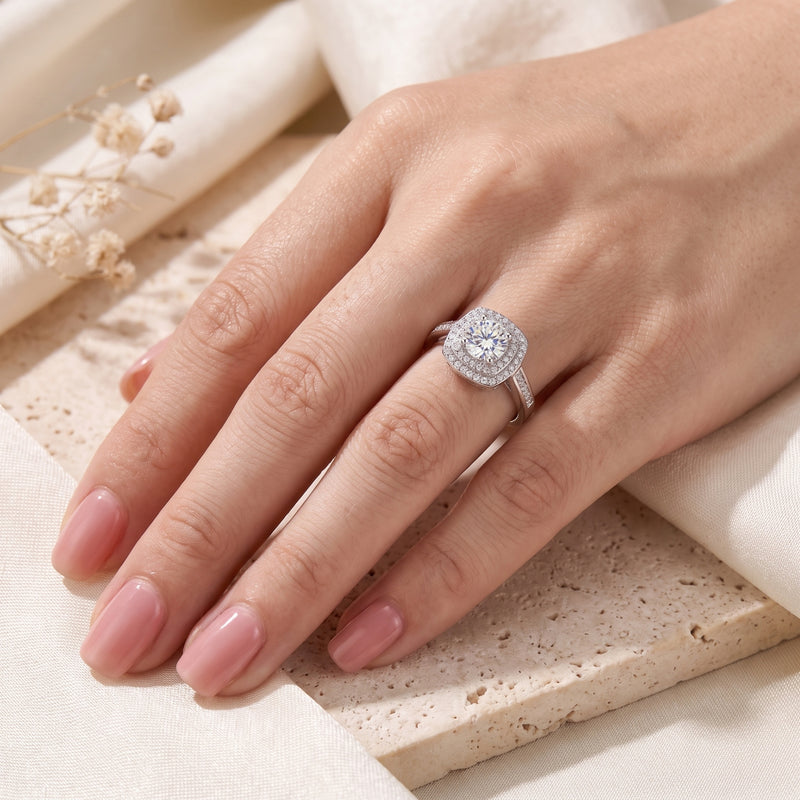 Full view of a hand wearing the silver double halo ring on the ring finger against a cream backdrop.