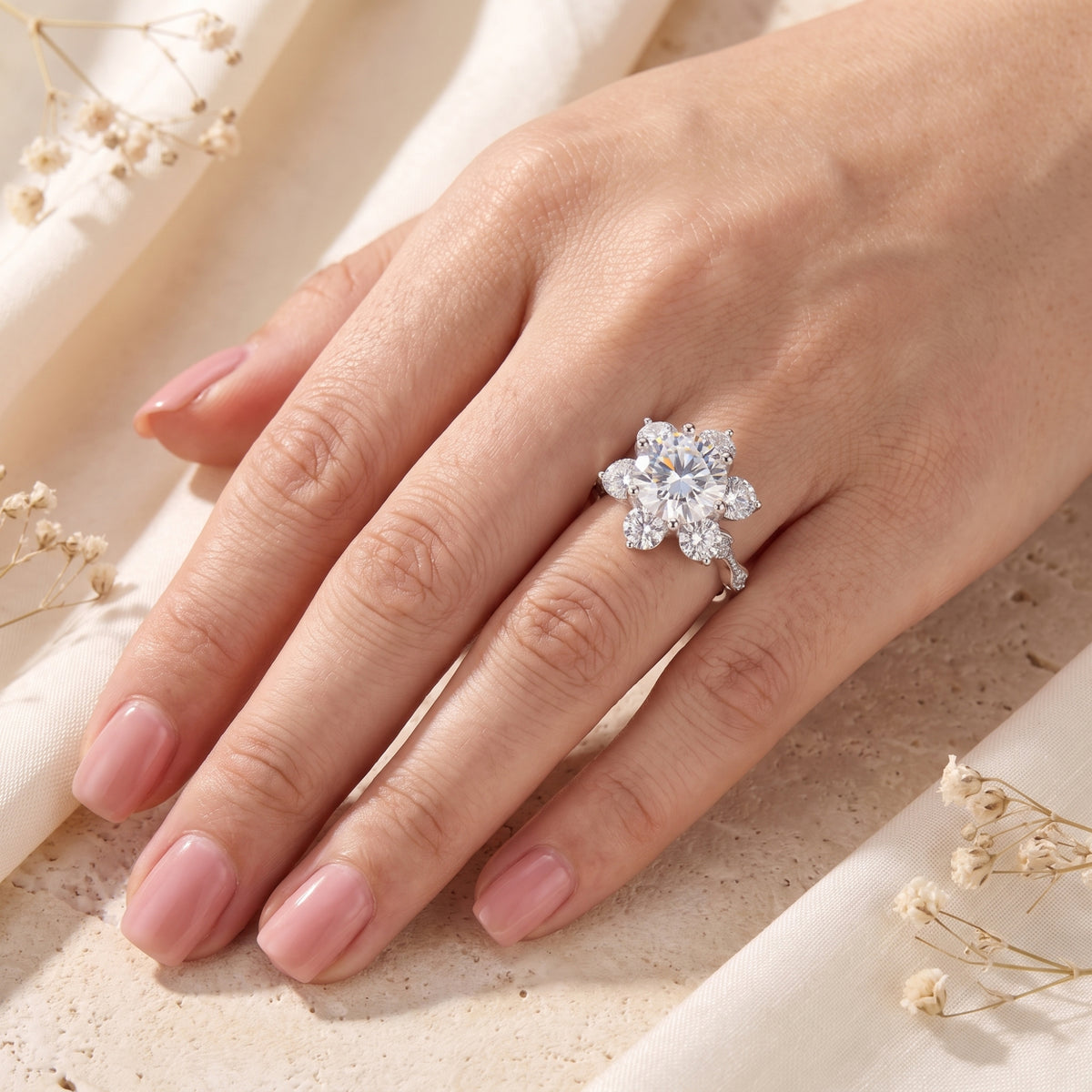Roselita silver flower ring with round simulated diamond worn on a woman's finger.