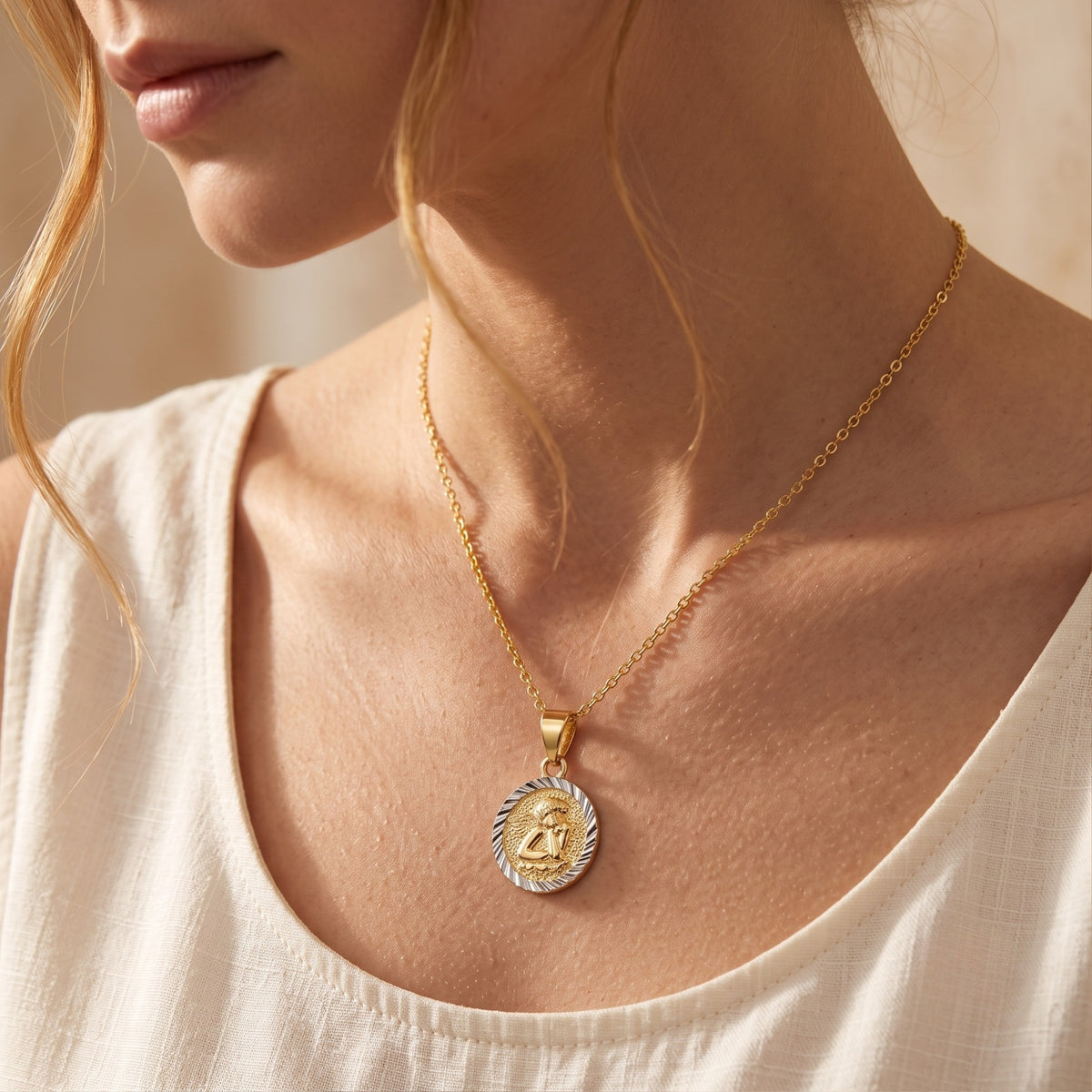 Side-profile close-up of a model wearing the gold-tone cherub pendant necklace over a cream top.