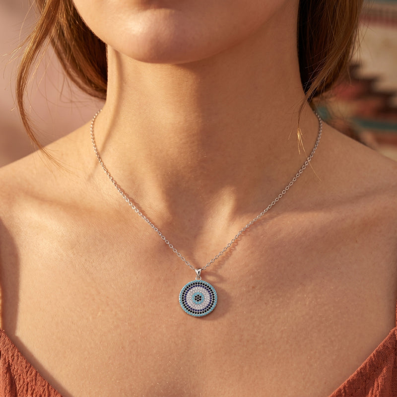Southwestern-inspired silver necklace with a circular turquoise pendant worn by a model.