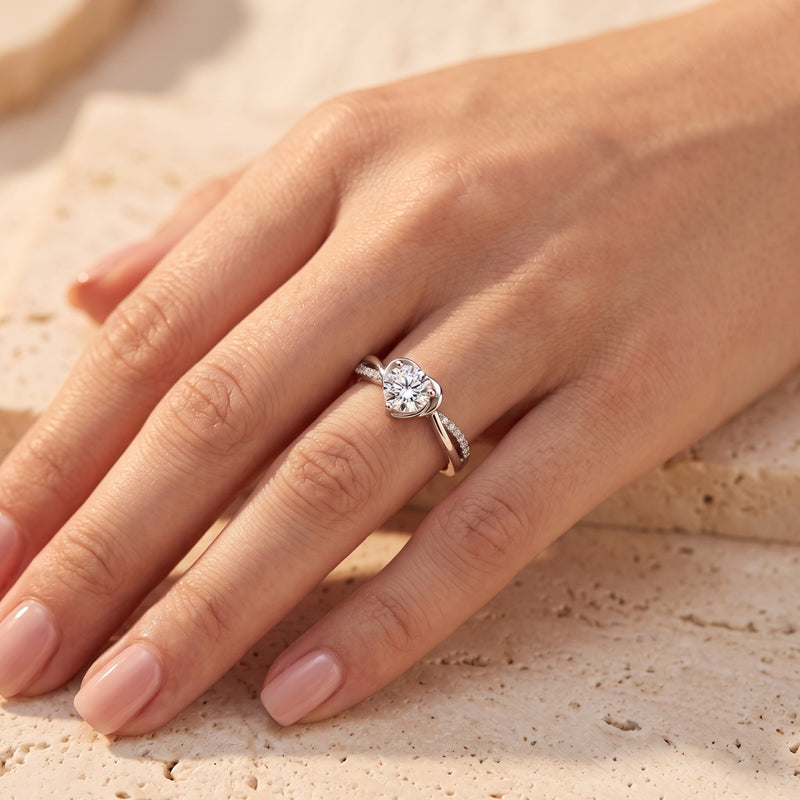 Heart-shaped sterling silver bypass ring with a brilliant simulated diamond worn on a woman's finger.
