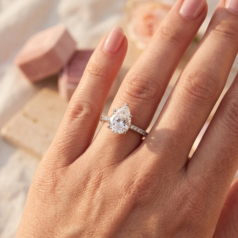 Pear-cut simulated diamond promise ring in sterling silver worn on a woman's finger.