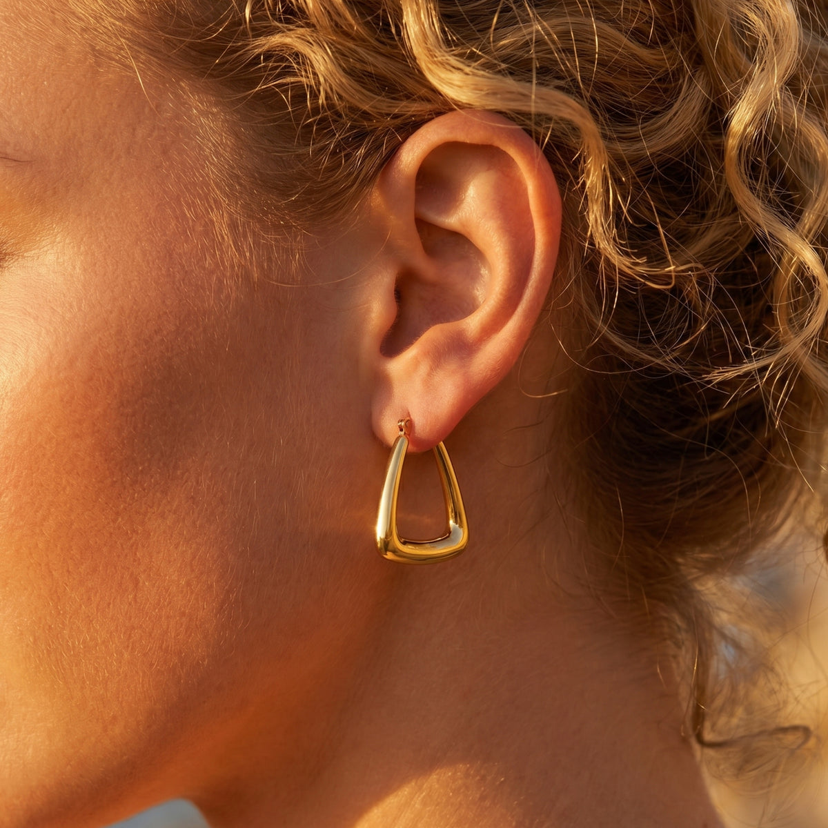 Gold 18K PVD stainless steel triangle hoop earring on ear.
