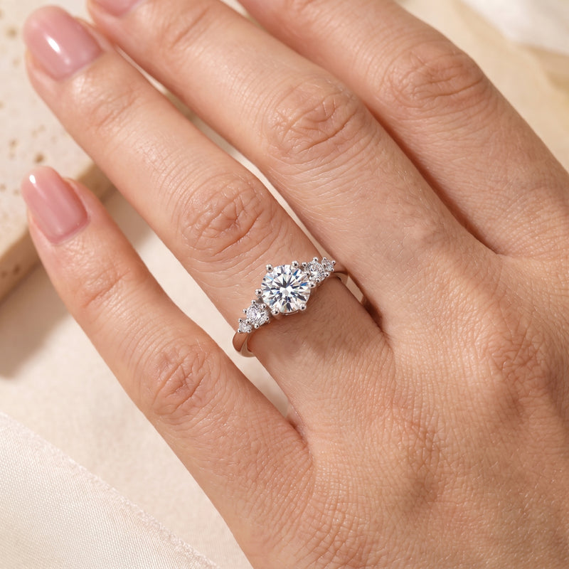 Close-up of the silver ring with a round center stone and clustered side accents worn on a hand