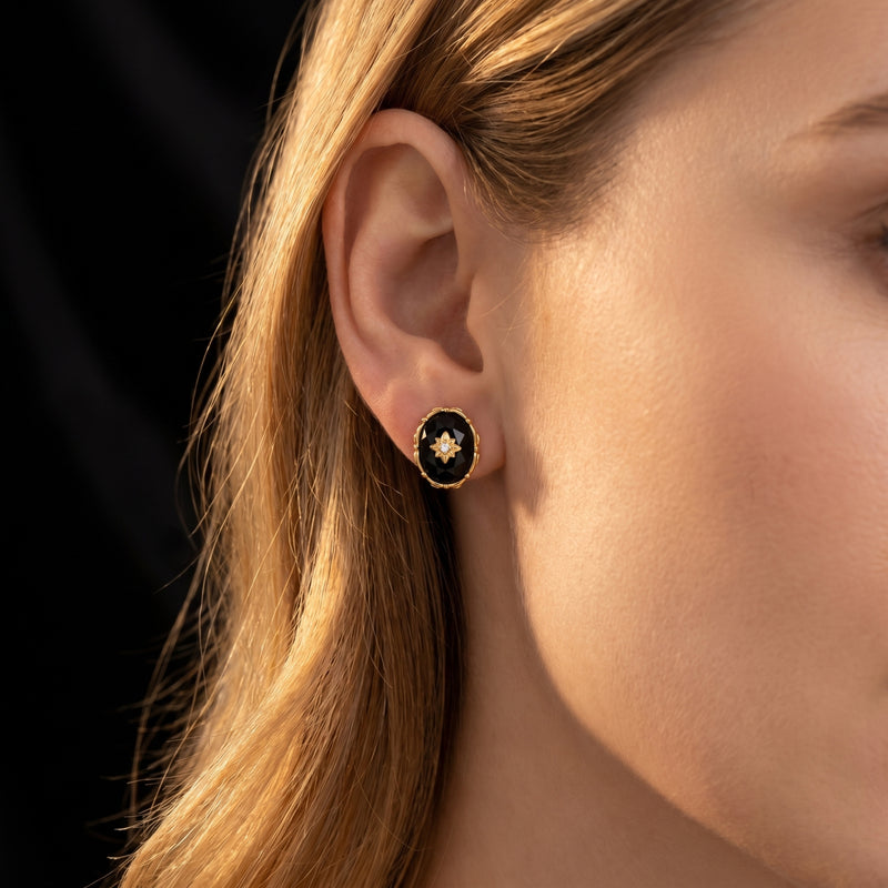 Model wearing a yellow gold oval-cut faceted black onyx drop earring with a gold starburst center.
