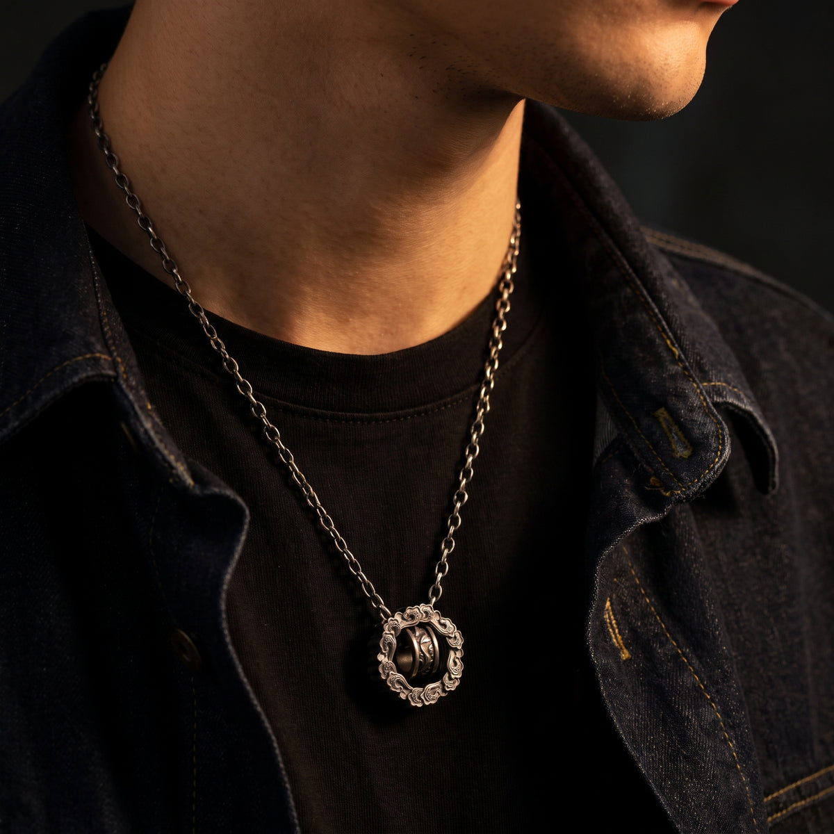 Model wearing the silver cloud wheel pendant over a black top and dark denim jacket.