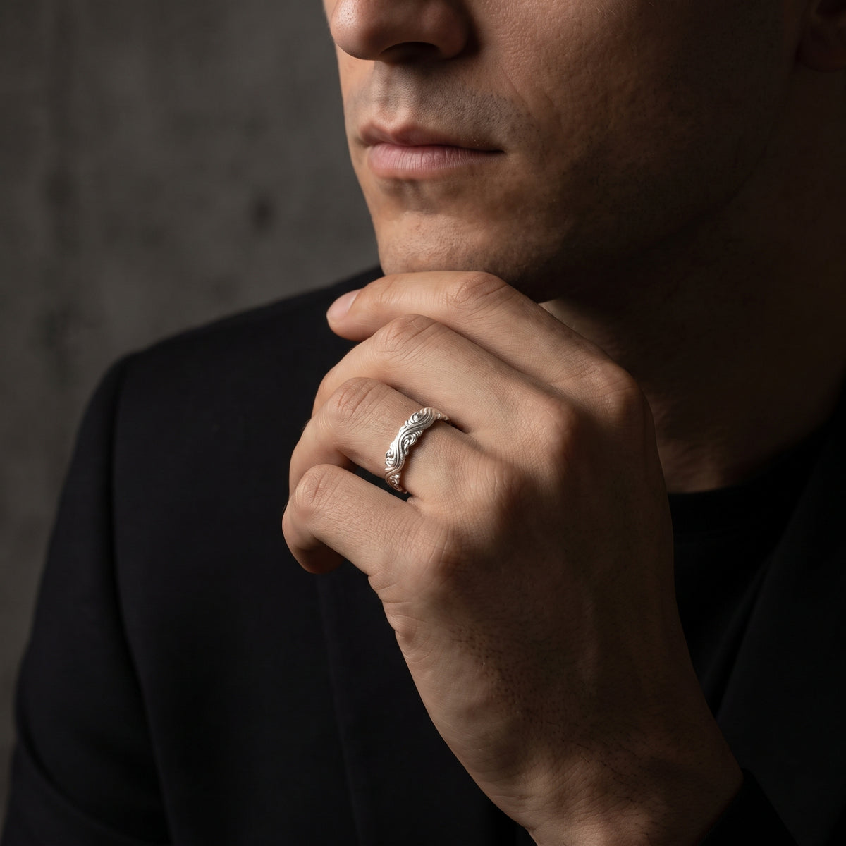 Man wearing the silver wave scroll open ring on his ring finger with his hand resting under his chin.