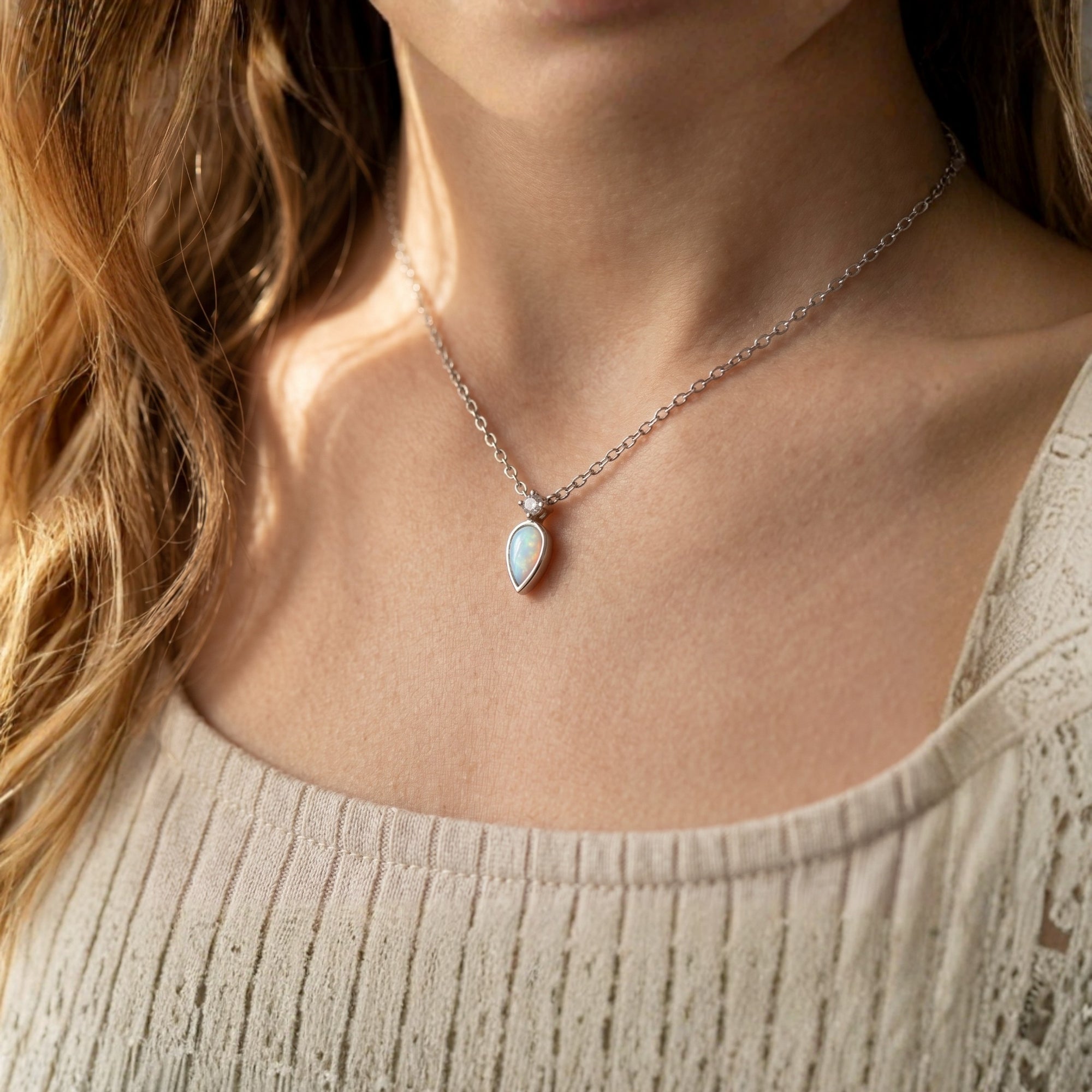 Woman wearing the silver Elyse necklace featuring a teardrop white opal pendant and diamond accent.