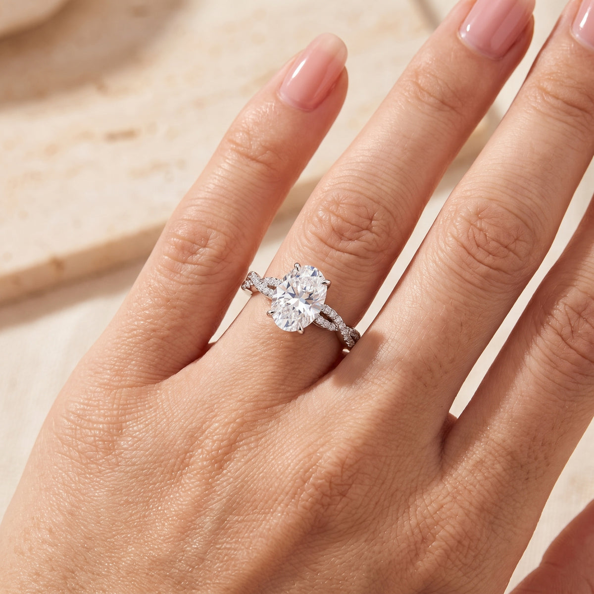 Top-down view of the silver twist ring with an oval center stone worn on a hand.