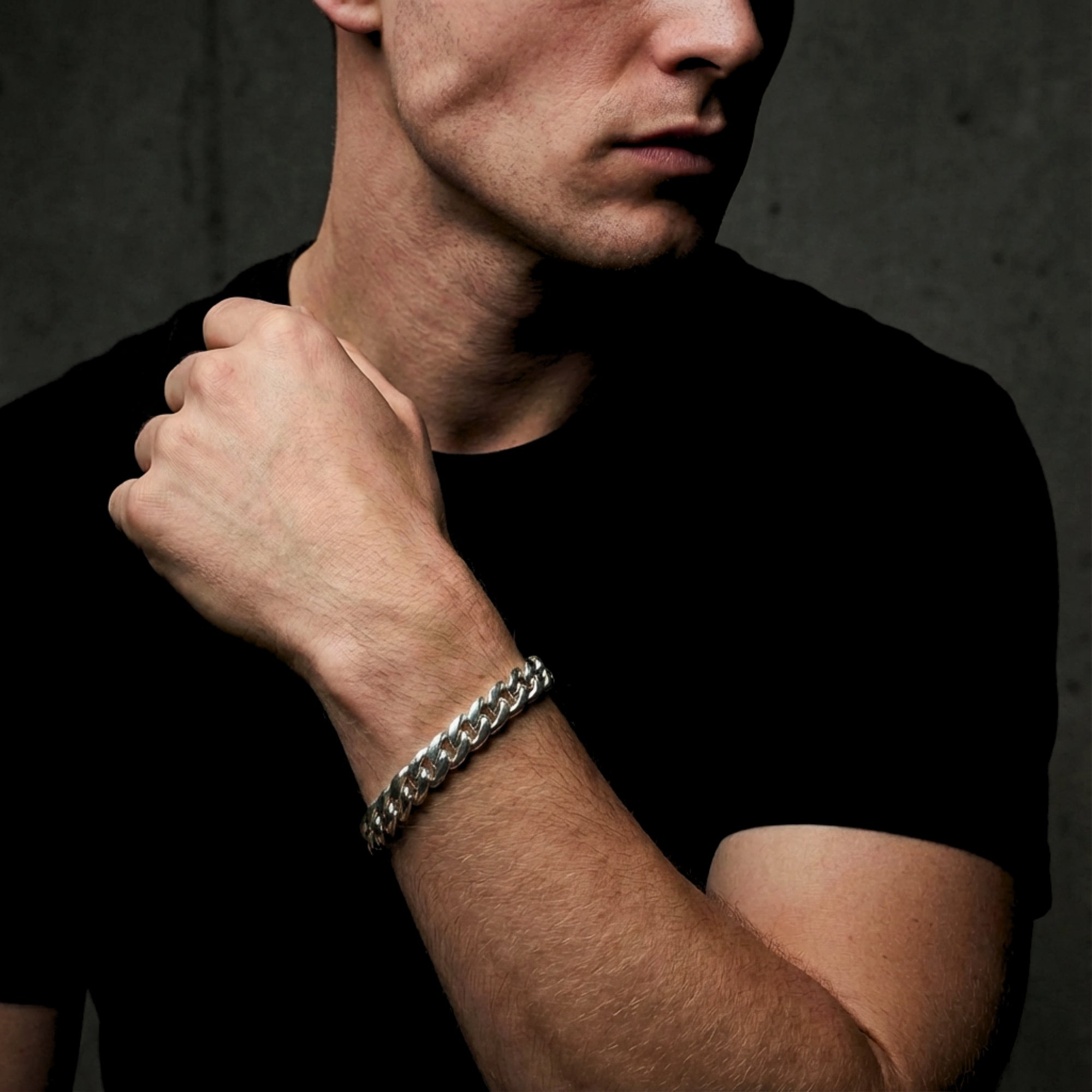Men's silver stainless steel Cuban link bracelet worn on a wrist, paired with a black t-shirt.