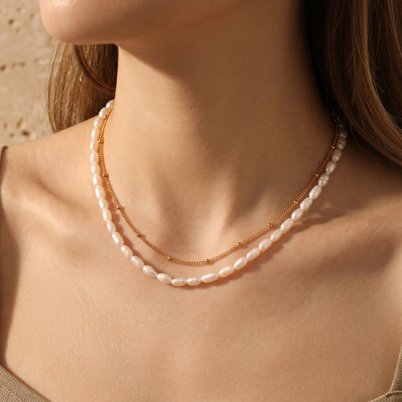 Chiara layered gold necklace with satellite chain and white freshwater pearls worn by a model.