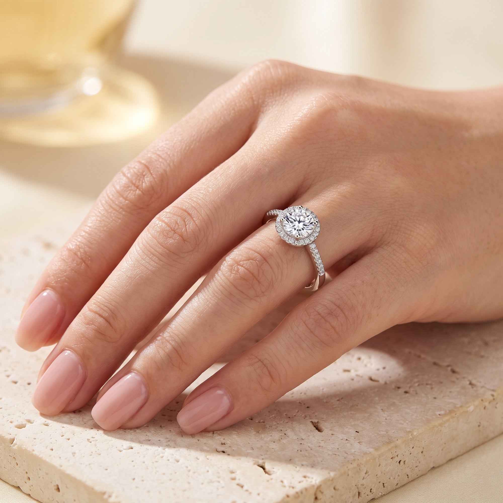 Sterling silver Cassielle ring with a round-cut simulated diamond halo worn on a woman's hand.