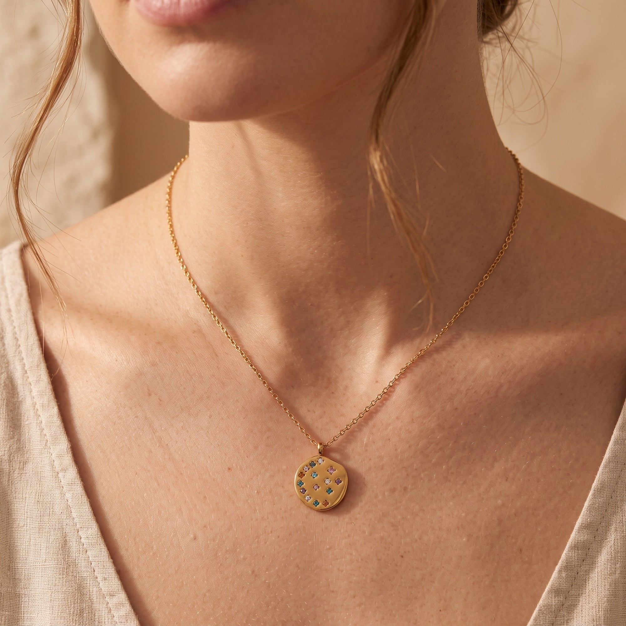 Model wearing the 18K gold Astraline pendant necklace featuring a circular medallion with rainbow CZ crystals.