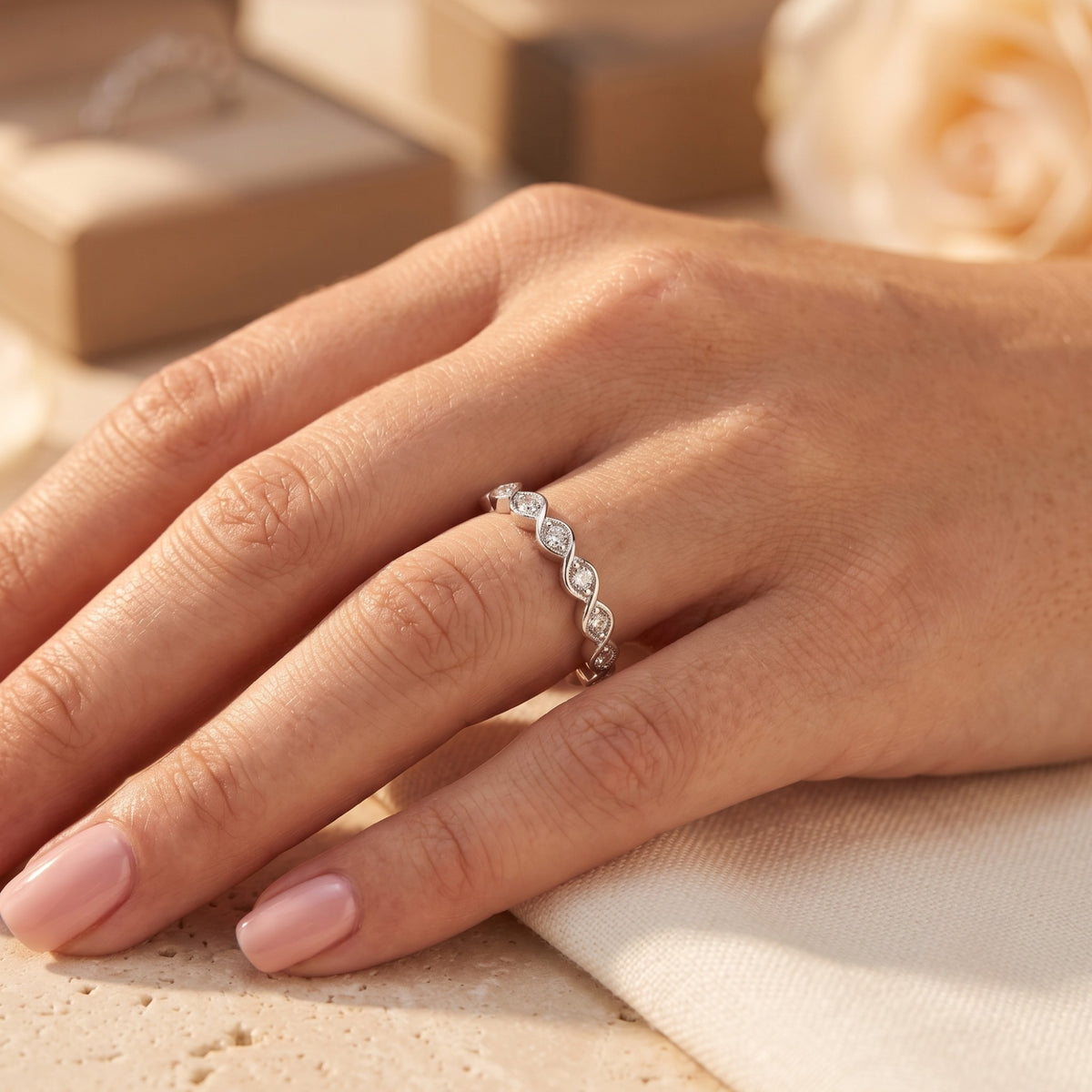 The Amandelle sterling silver infinity band with round simulated diamonds worn on a woman's hand.