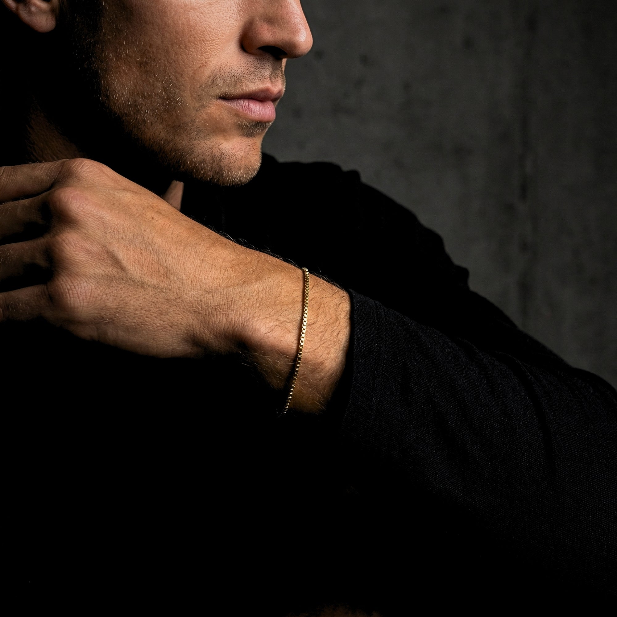 Men's gold stainless steel box chain bracelet worn on a wrist with a black long-sleeve shirt.