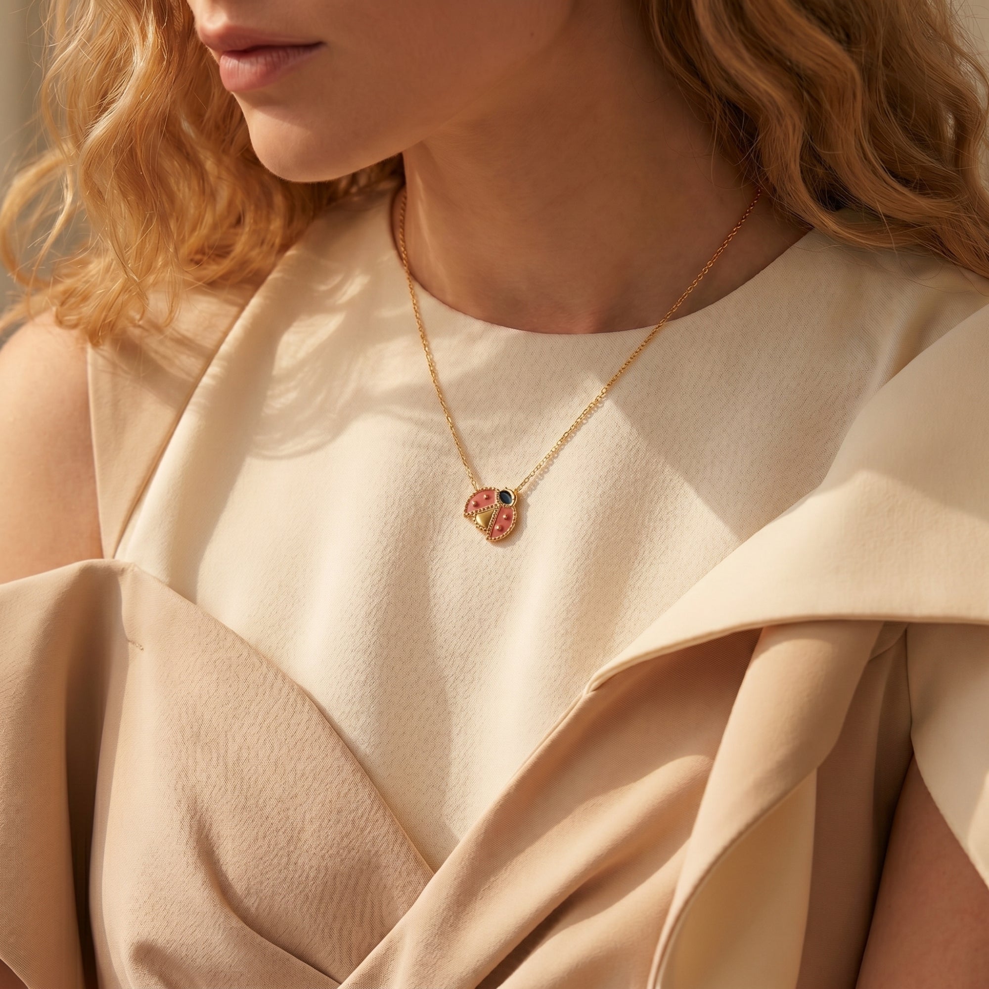 Gold ladybug charm necklace worn on a model's neck.