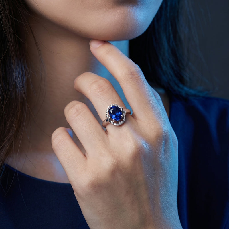 Model wearing the 18K white gold Karyna oval tanzanite and diamond halo ring on her ring finger.