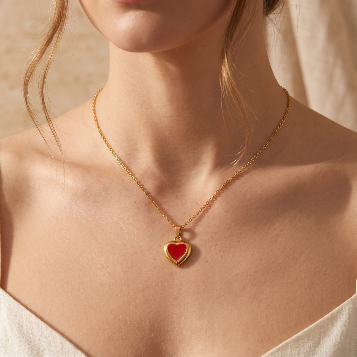 Front view of a model wearing the red enamel heart necklace centered on her upper chest.