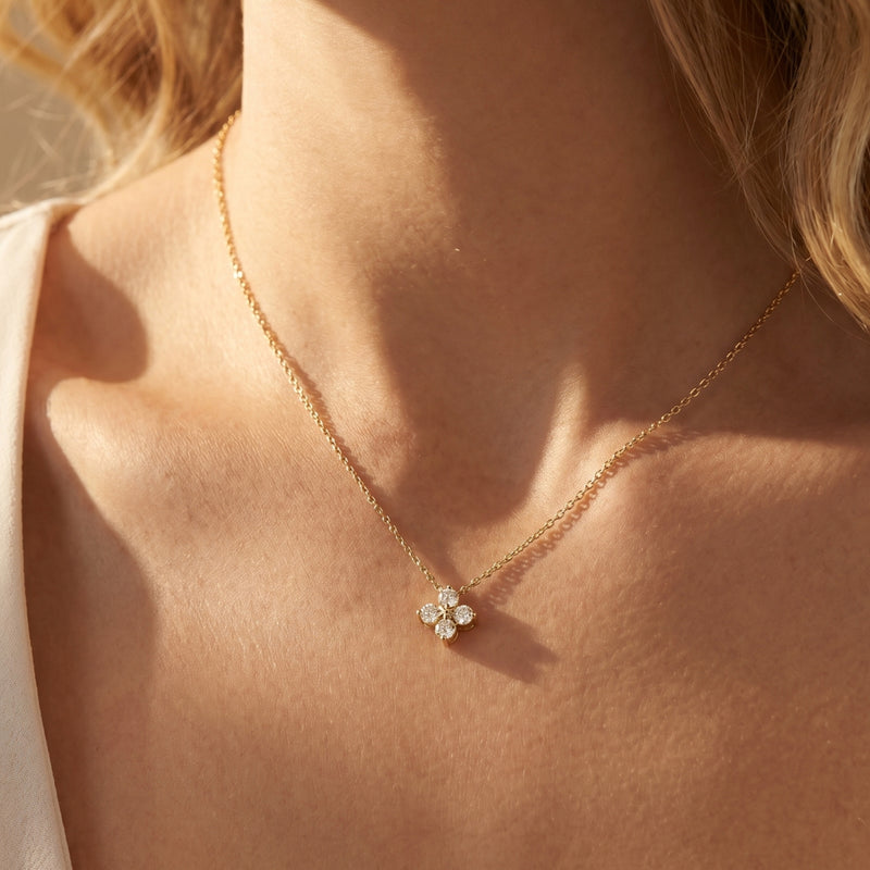 Gold Fioris flower necklace with round moissanite stones worn on a woman's neck.
