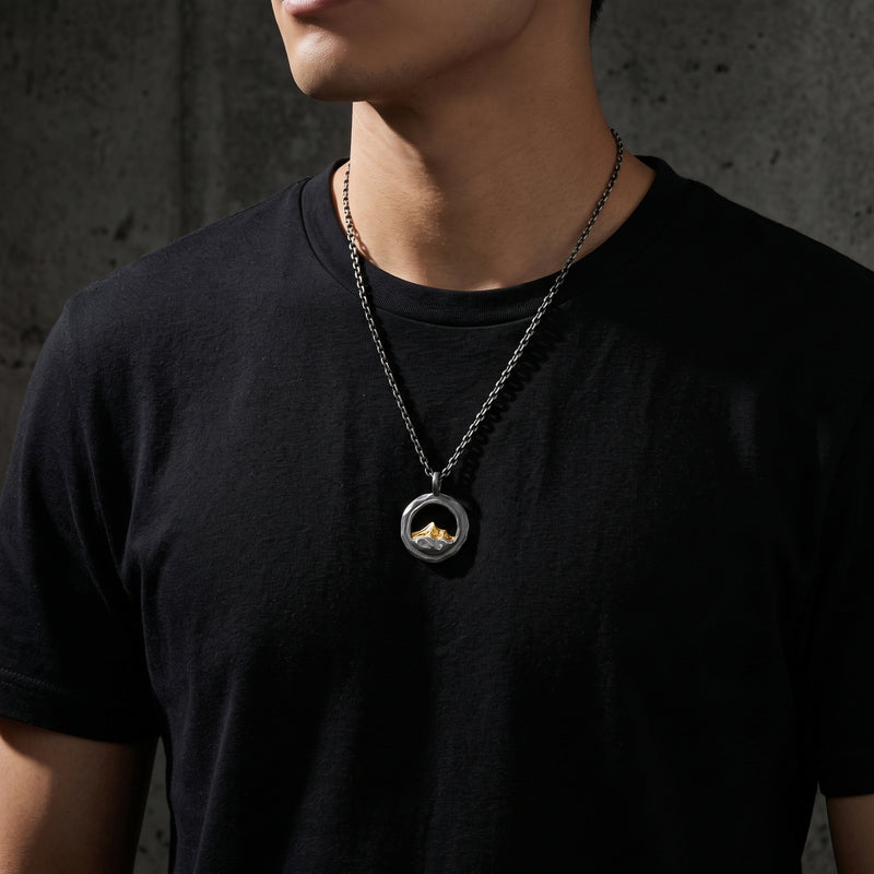 Male model wearing the silver and gold-tone mountain pendant necklace over a black T-shirt.