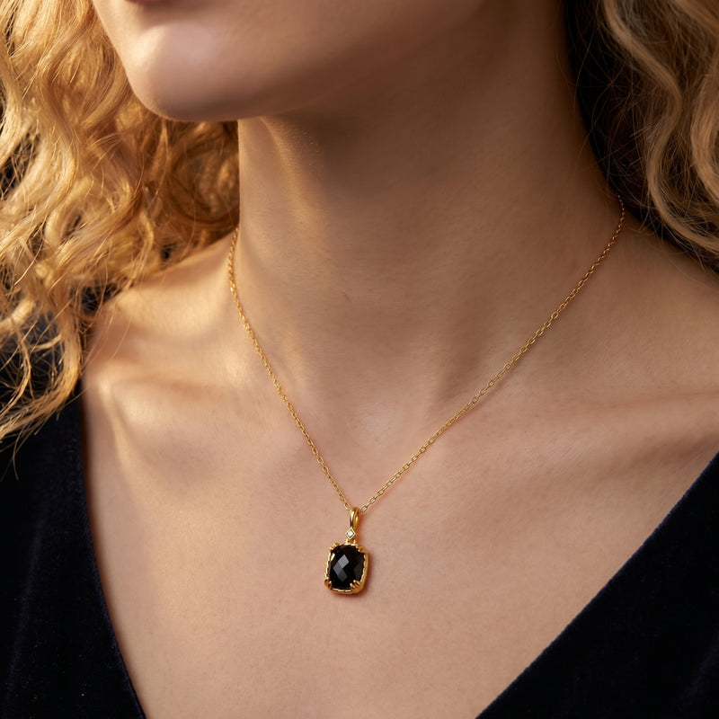 Model wearing the Eclipsia yellow gold necklace featuring a faceted cushion-cut black onyx pendant.
