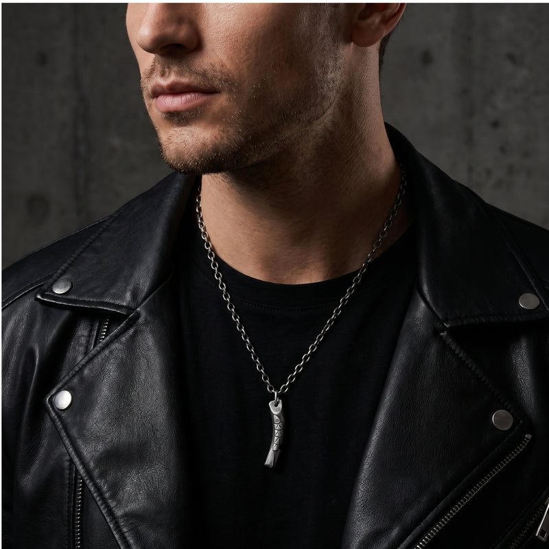 Man wearing the silver carved fish pendant necklace over a black shirt and under a leather jacket.