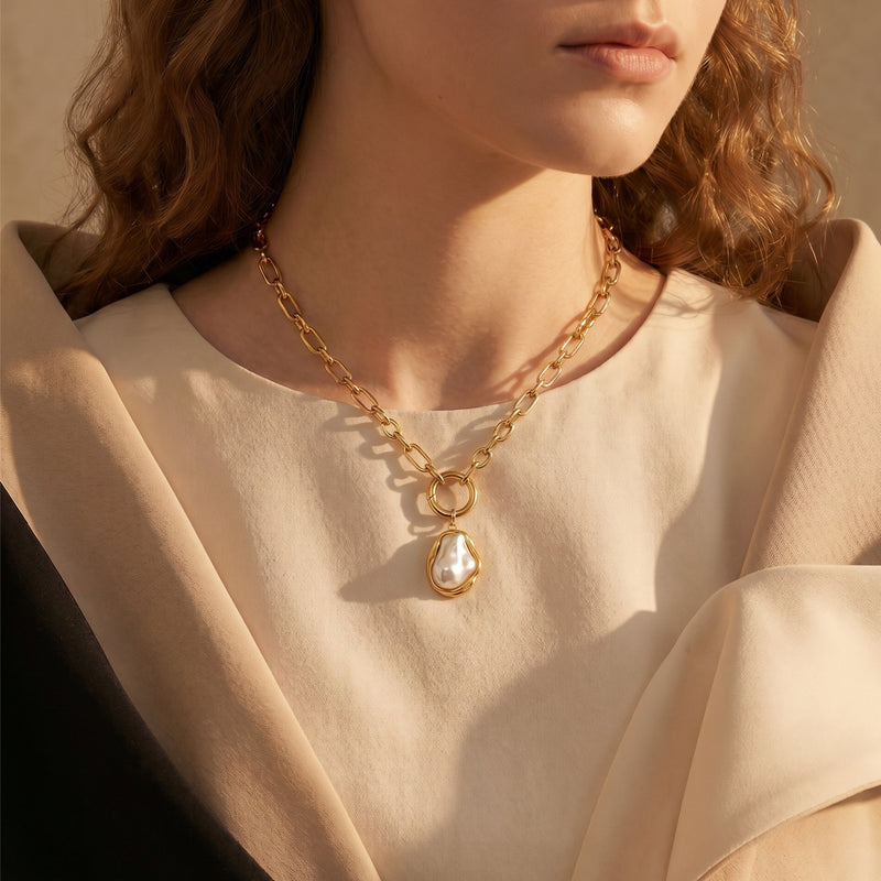 Model wearing the gold Isabella pearl necklace featuring an irregular synthetic pearl.