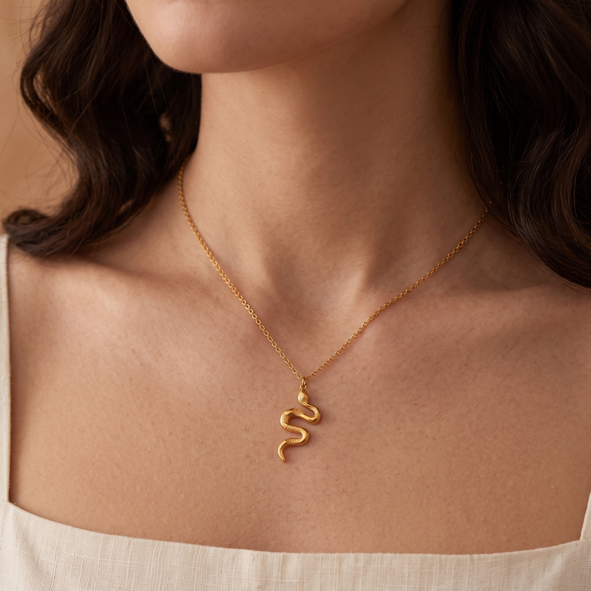 Close-up of a person wearing the gold-tone serpent pendant necklace centered on the upper chest.