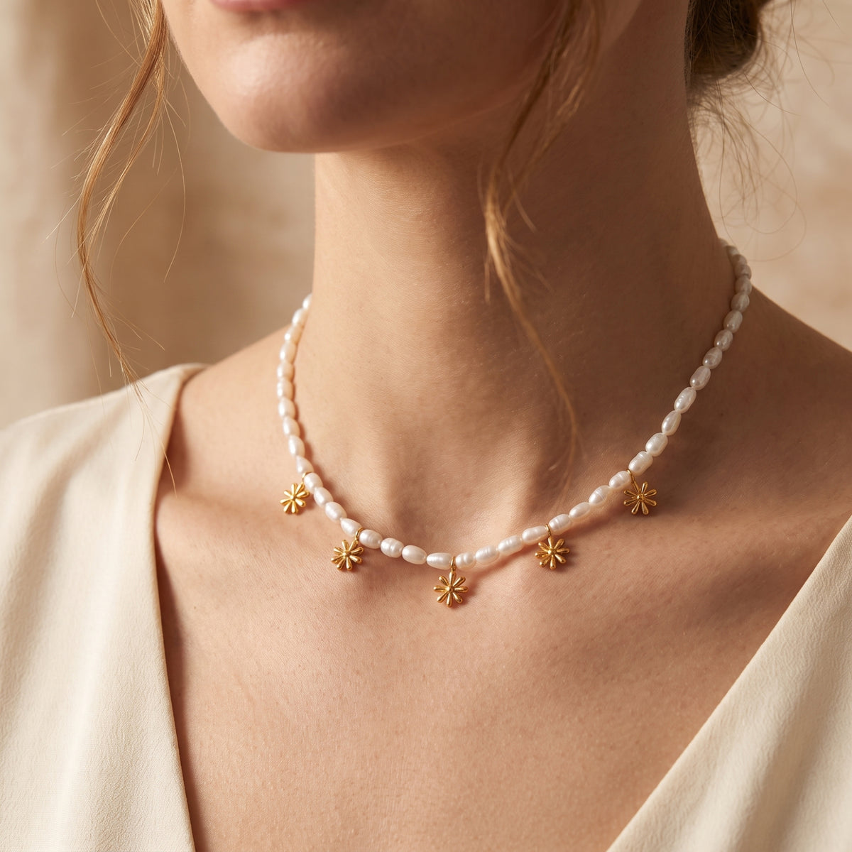 Model wearing a white pearl bead necklace with five gold-tone daisy charms around her neck.