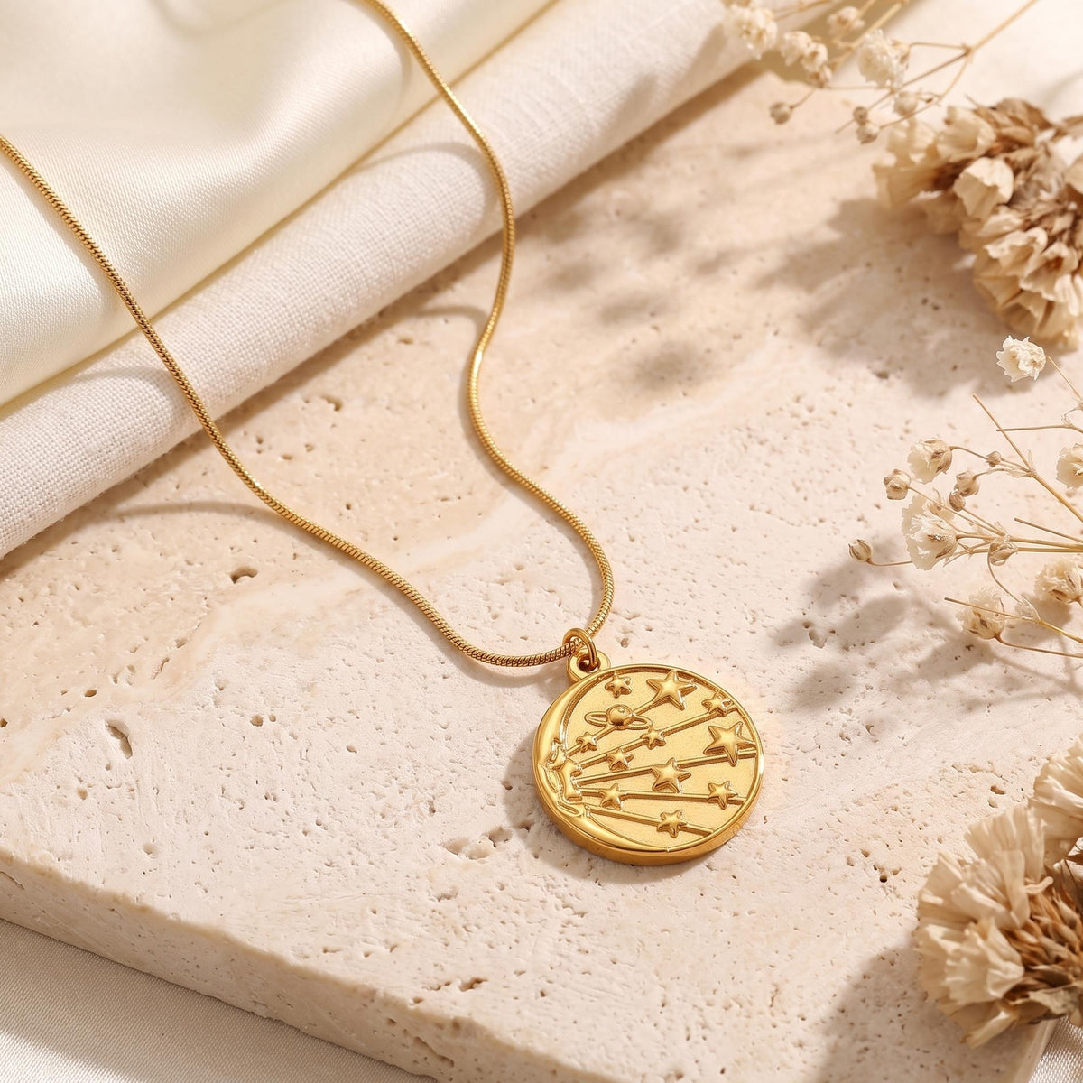 Close-up of the 18K gold celestial medallion pendant with star details on stone.