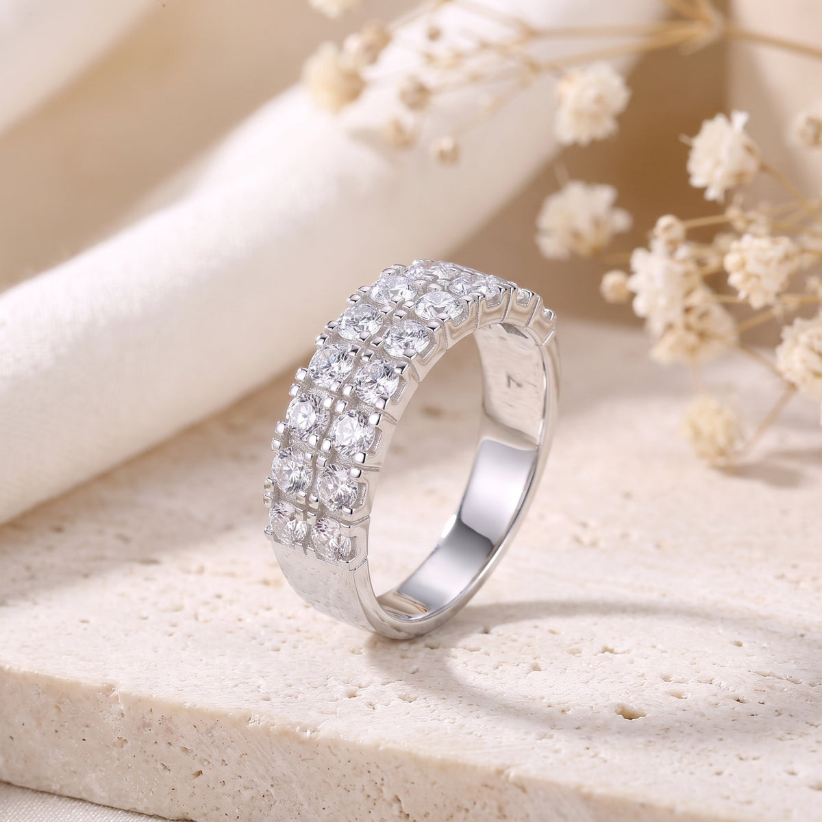 Angled view of the double-row silver ring with clear round stones, showing the smooth band profile.