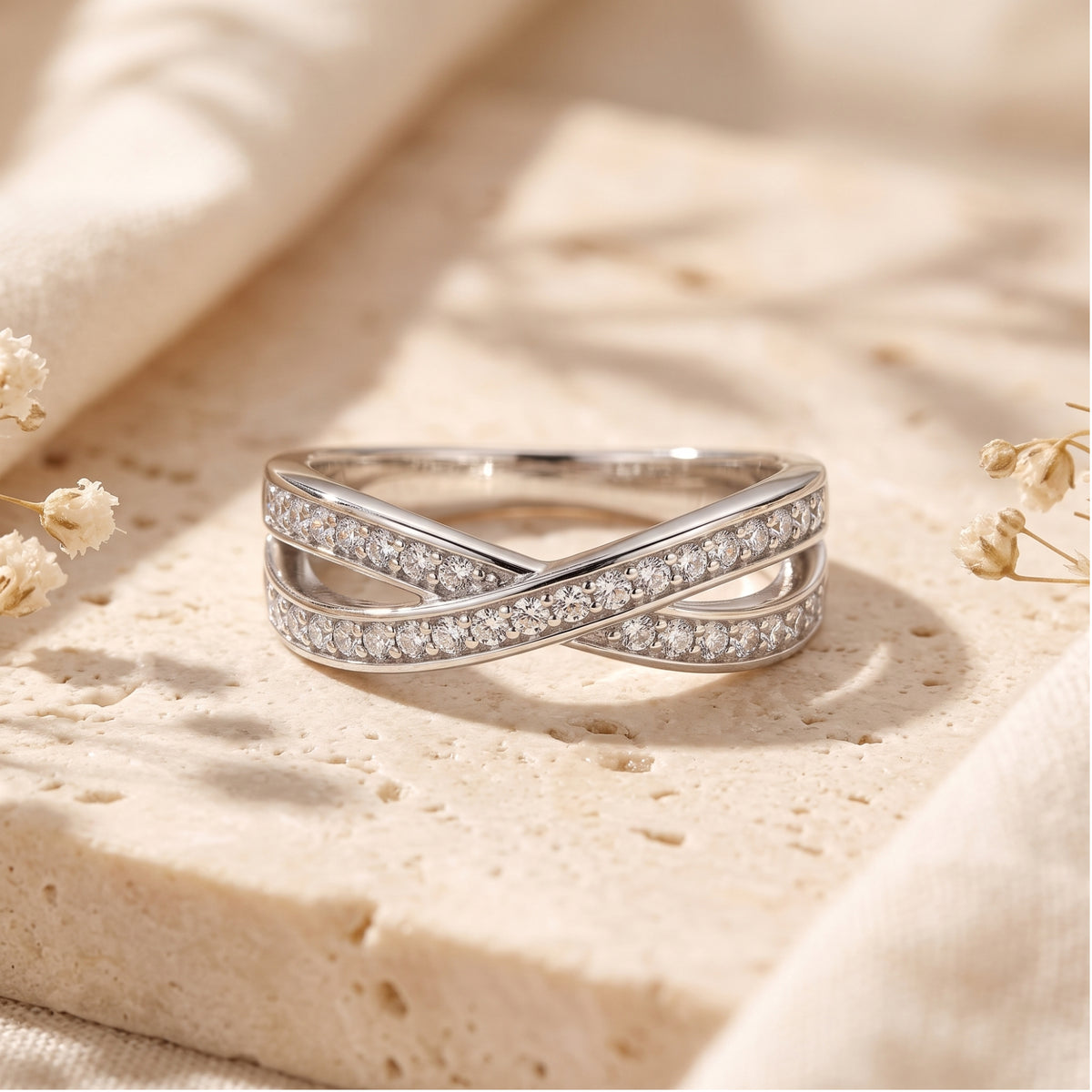 Close-up of the silver crossover ring showing pavé-set round cubic zirconia stones.