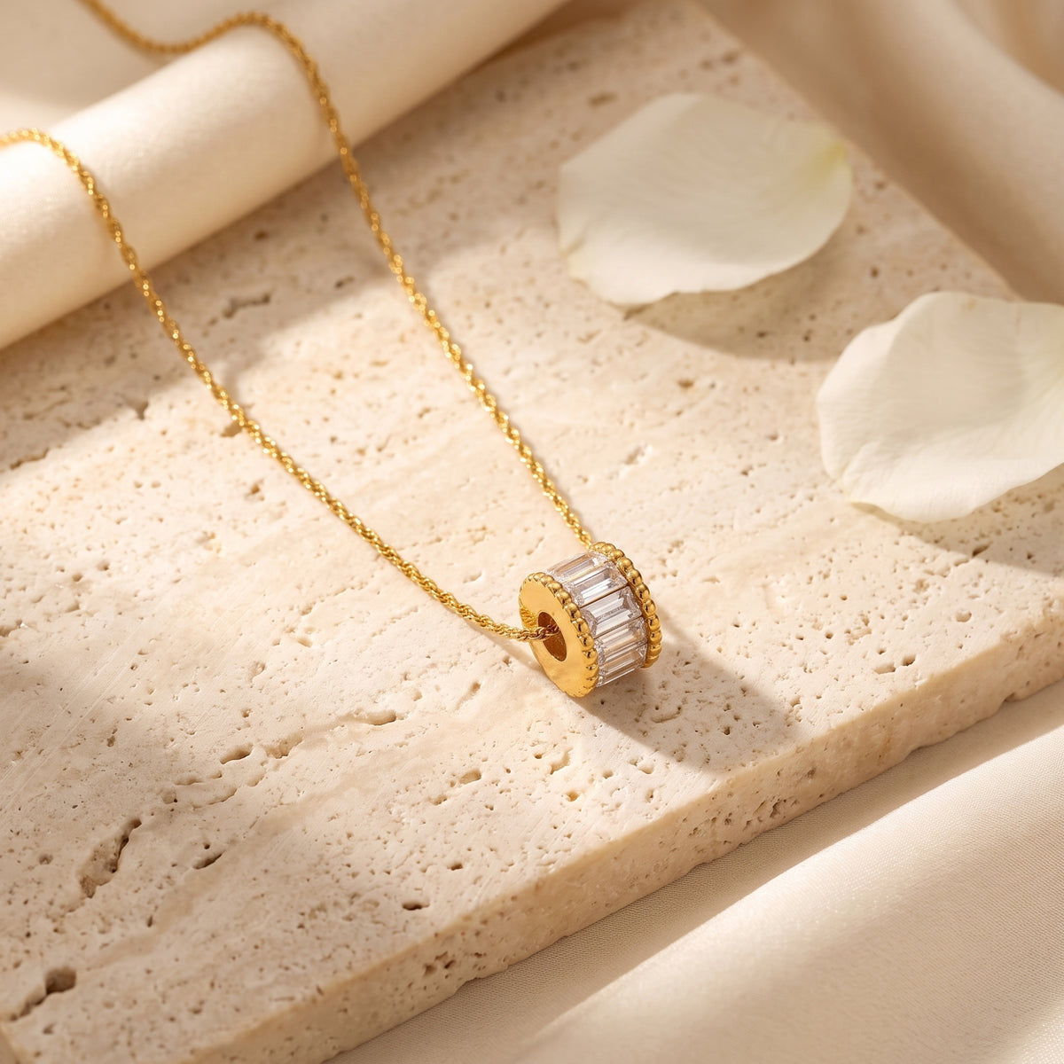 Close-up of a gold cylindrical pendant featuring baguette-cut simulated diamonds on a textured stone.