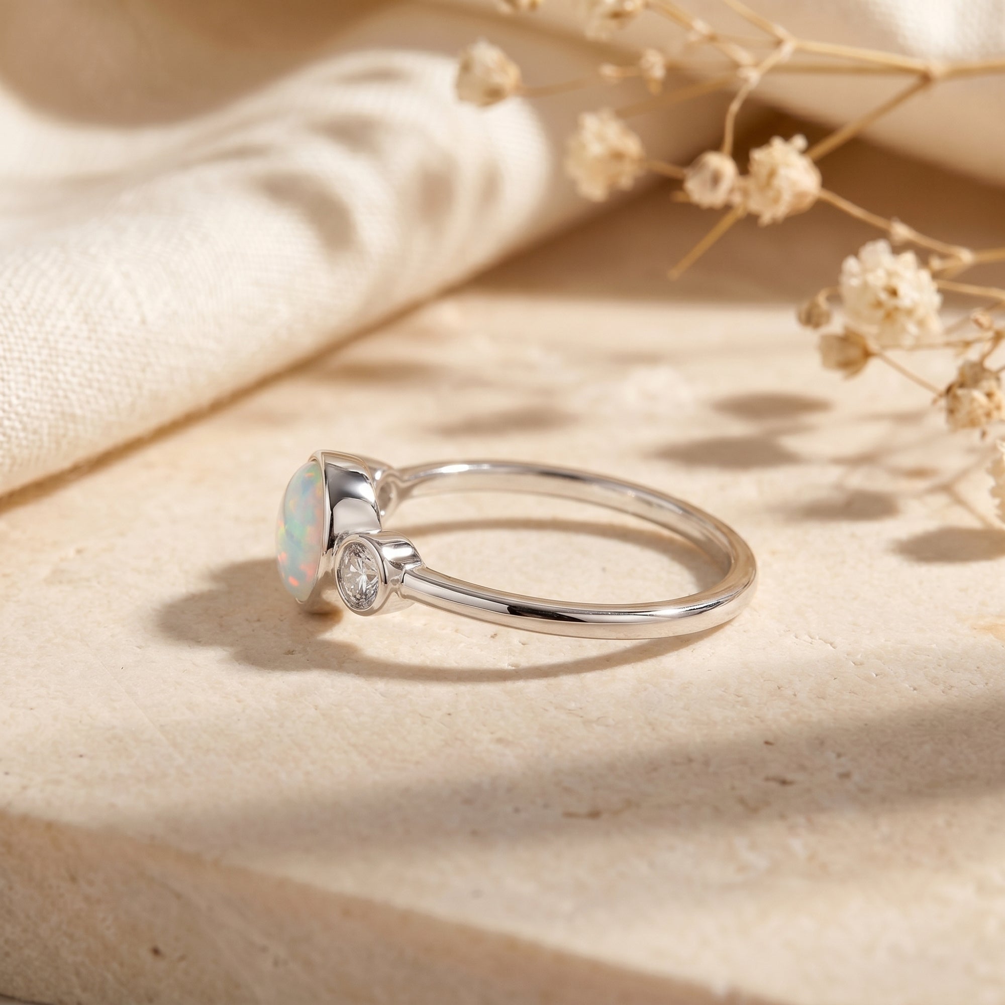 Side profile of a sterling silver three-stone ring showing the white opal cabochon and bezel setting.