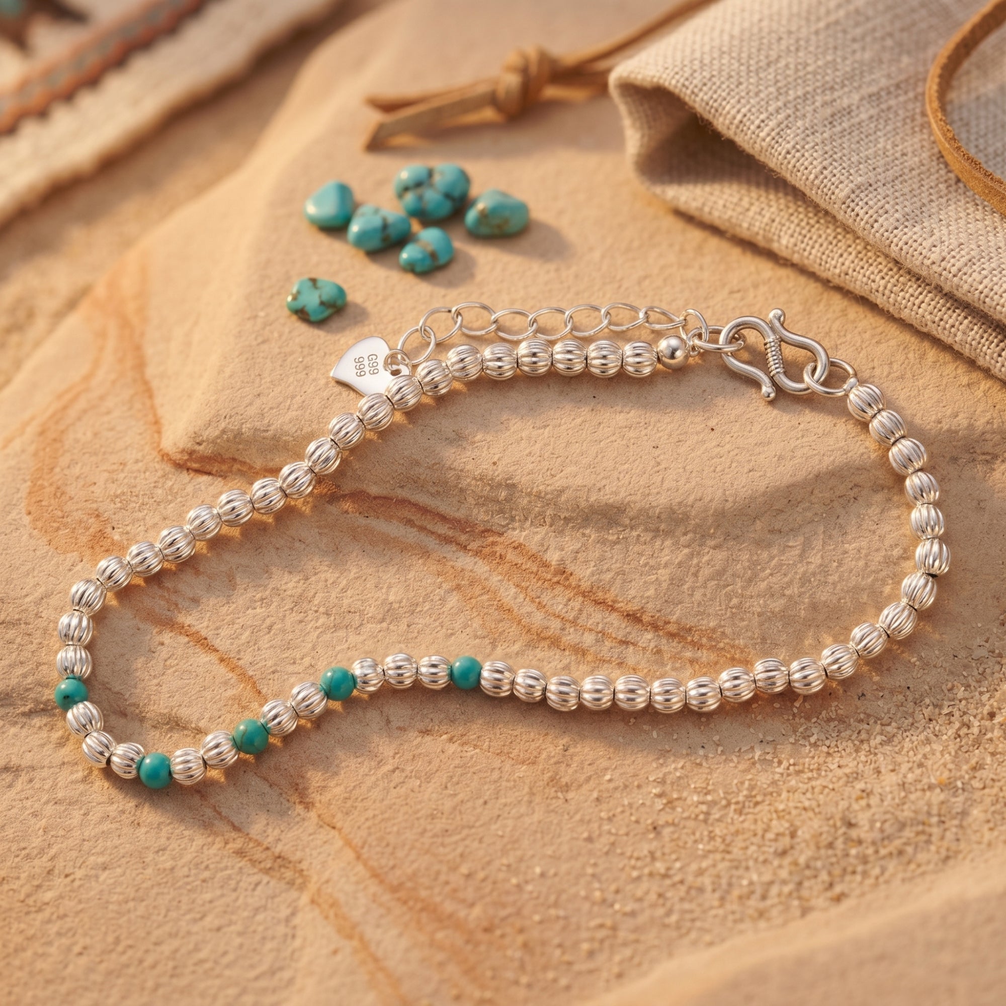 Detail of silver bead bracelet with turquoise and heart charm.