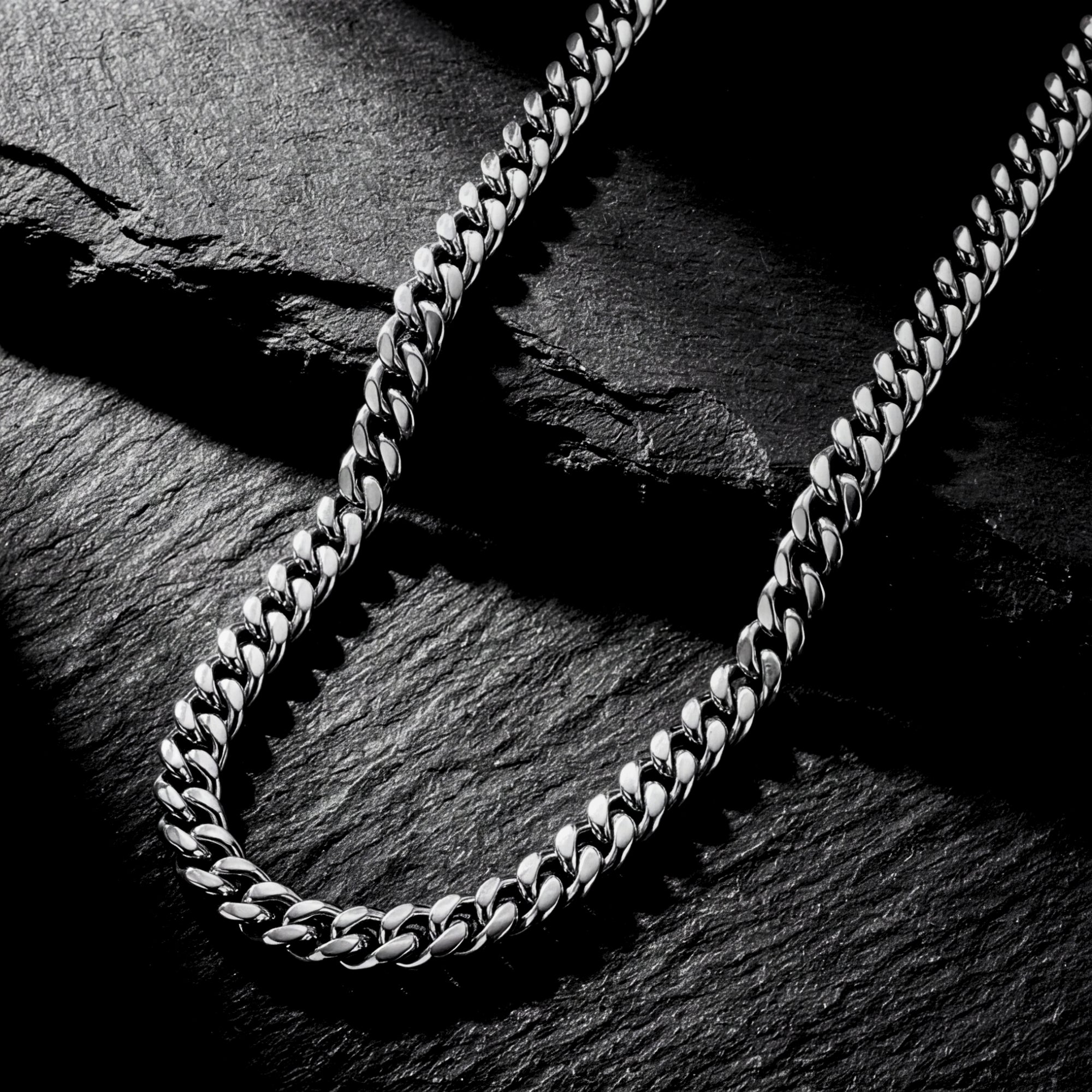 Silver 8mm stainless steel Cuban chain necklace displayed on a textured dark rock background.