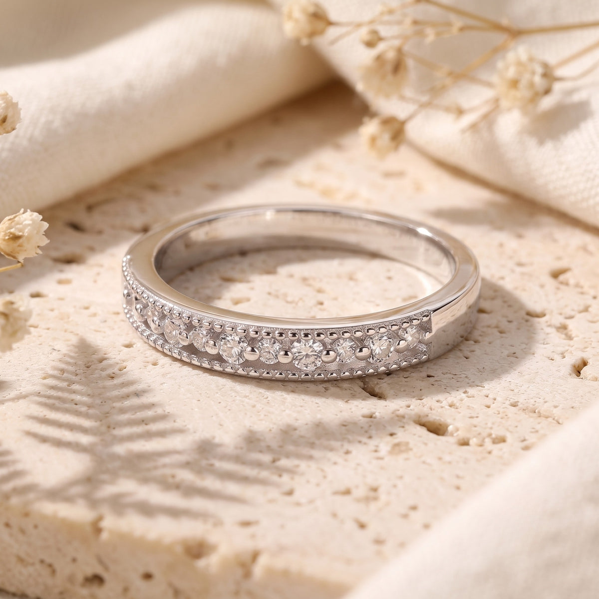 Horizontal view of the silver milgrain ring lying on stone, highlighting its row of clear stones.