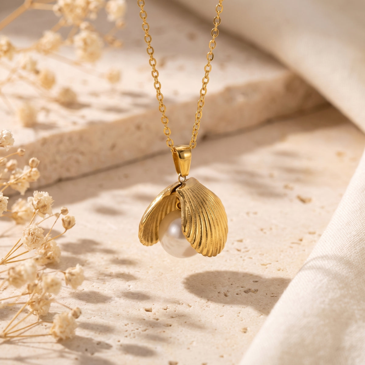Gold-tone shell pendant suspended from its chain, with a white pearl visible between the shell halves.