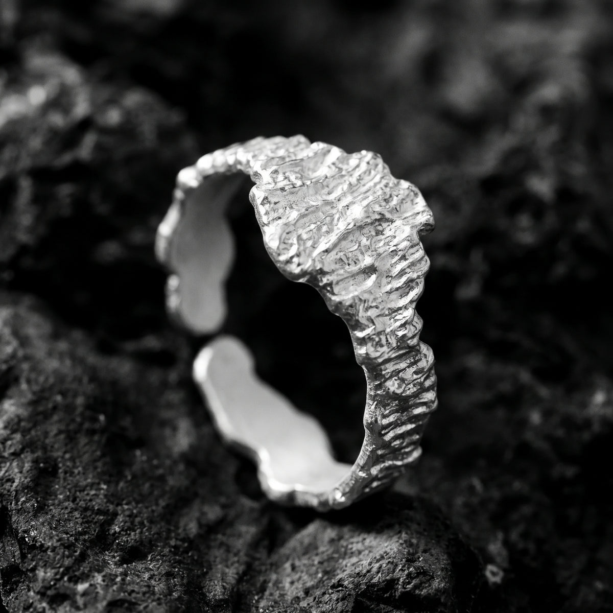 Angled close-up of the textured silver ring showing its open band and smooth inner surface.