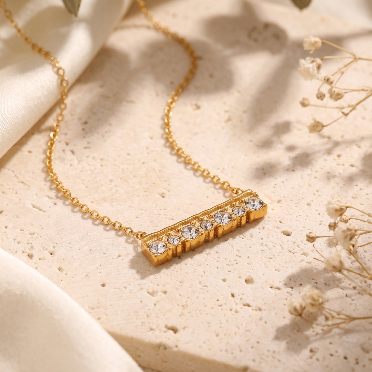 Close-up of the textured 18K gold finish bar pendant with seven brilliant-cut simulated diamond stones.