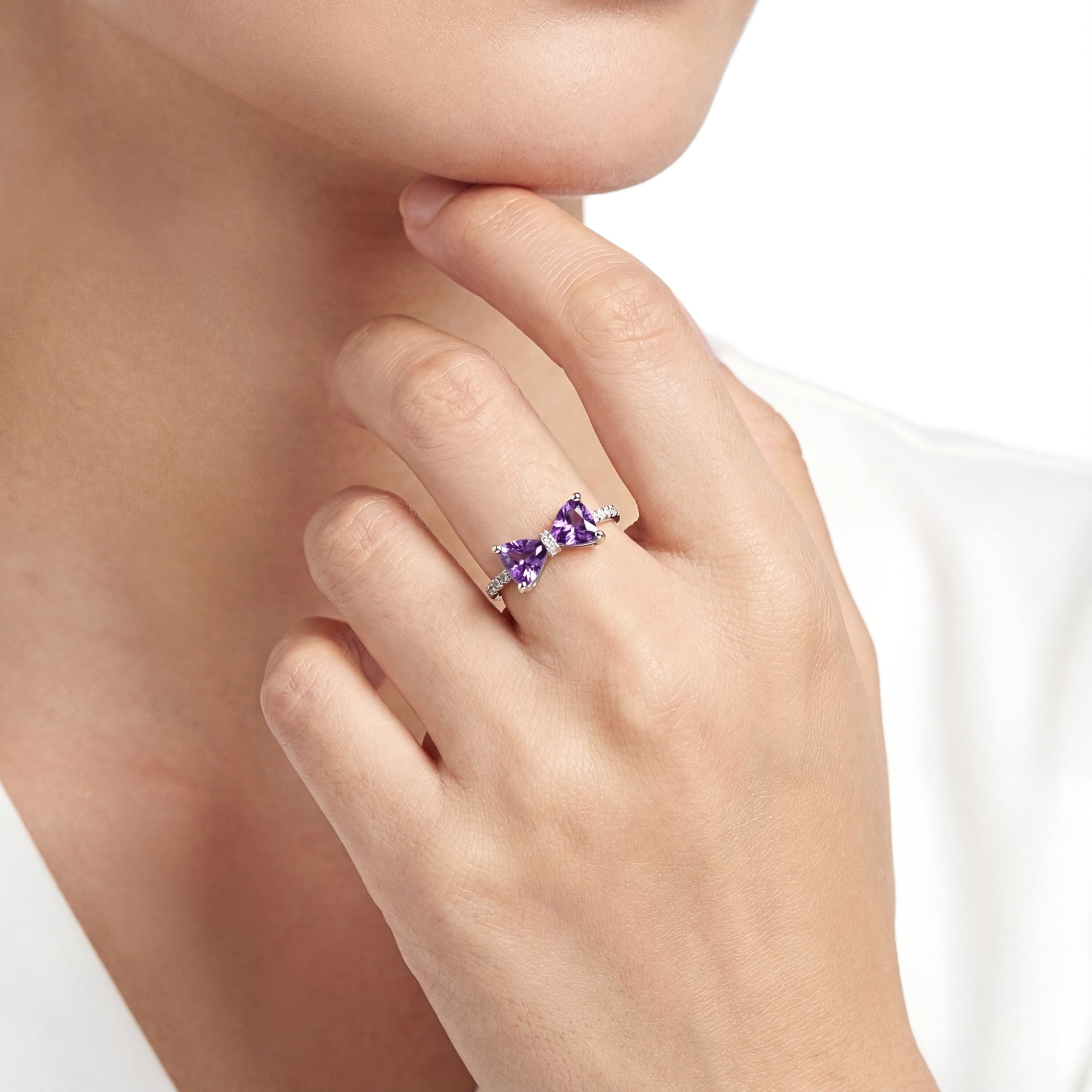 Sterling silver Violette bow ring with trillion-cut purple simulated amethysts worn on a model's finger.