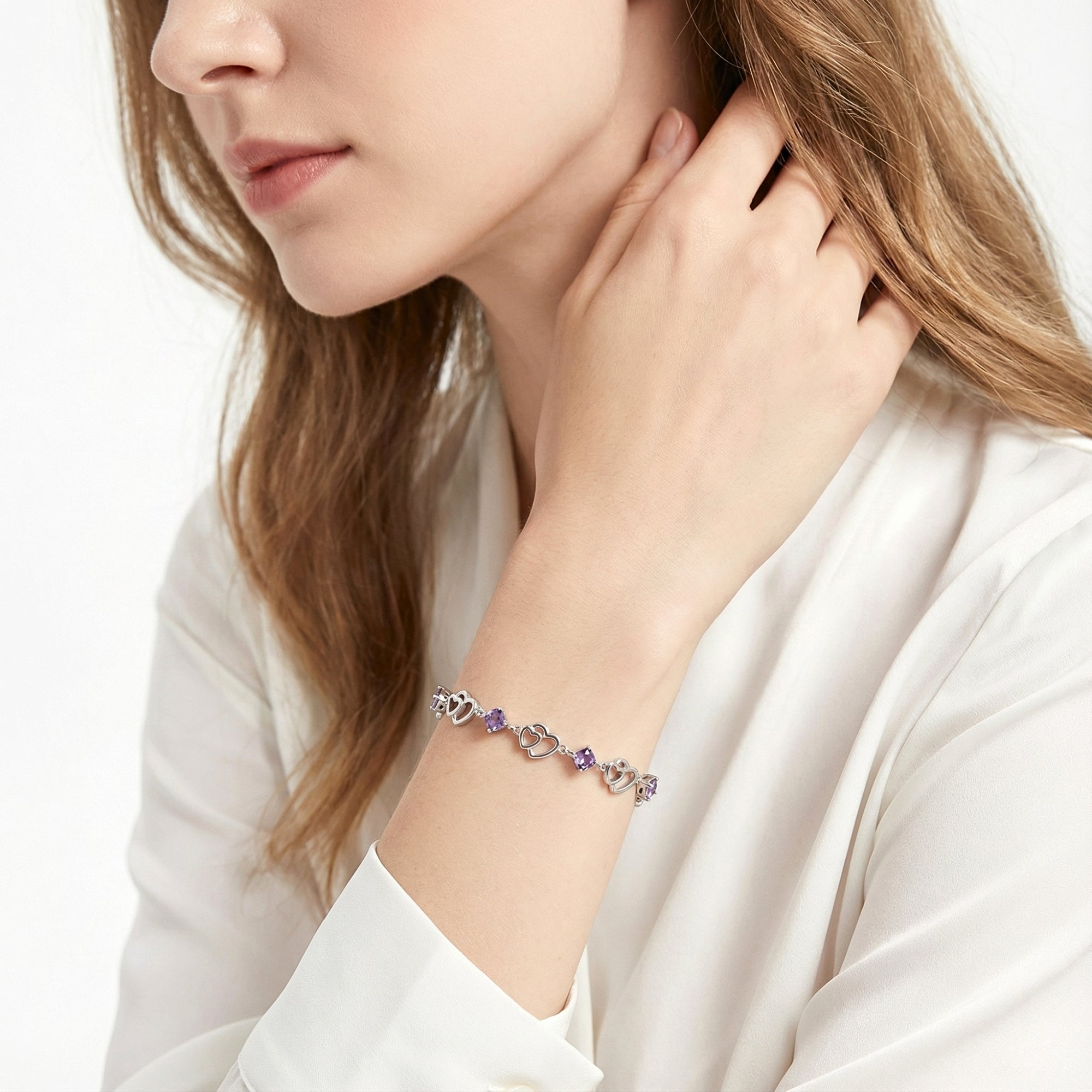 Woman wearing the sterling silver heart link bracelet with purple simulated amethyst stones on her wrist.