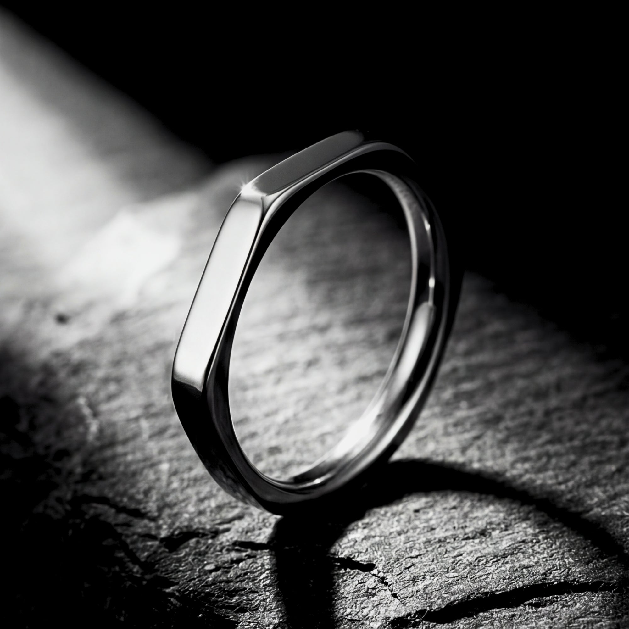 Silver Spartan signet ring in 316L stainless steel standing on a dark textured stone surface.