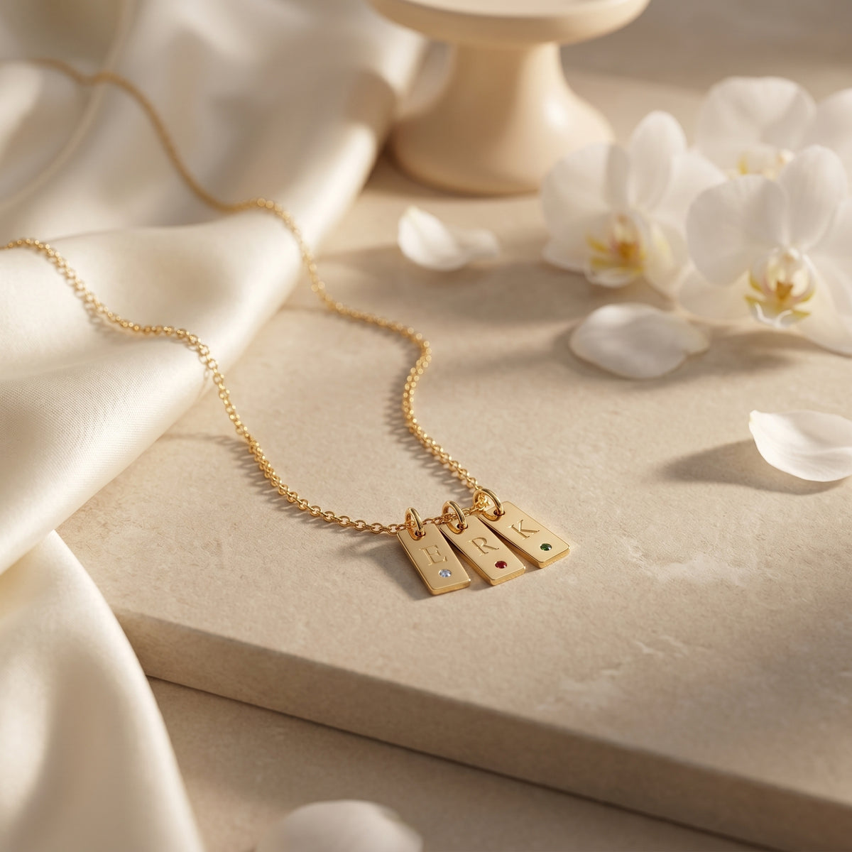 Close-up of the gold Cecelia pendant necklace featuring three engraved initial tags and colorful round birthstones.
