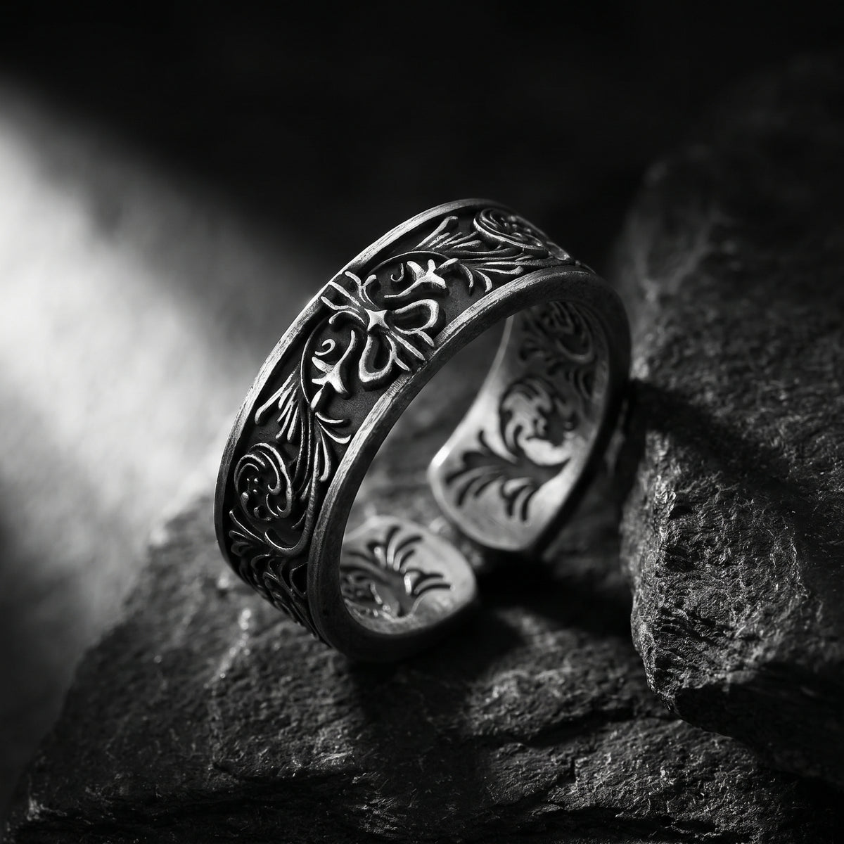 Angled view of the silver filigree open band ring resting on a dark rock surface.