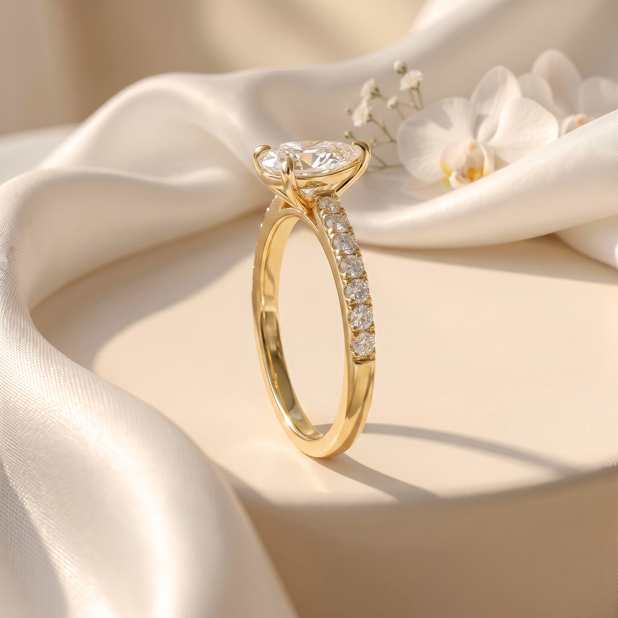 Side profile of a yellow gold pear-cut moissanite engagement ring with a paved band.