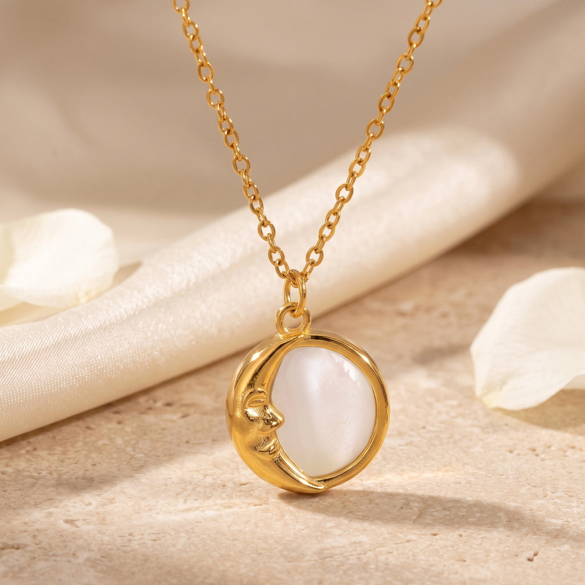 Front view of the gold-tone crescent moon and pearlescent inlay pendant hanging from its chain.