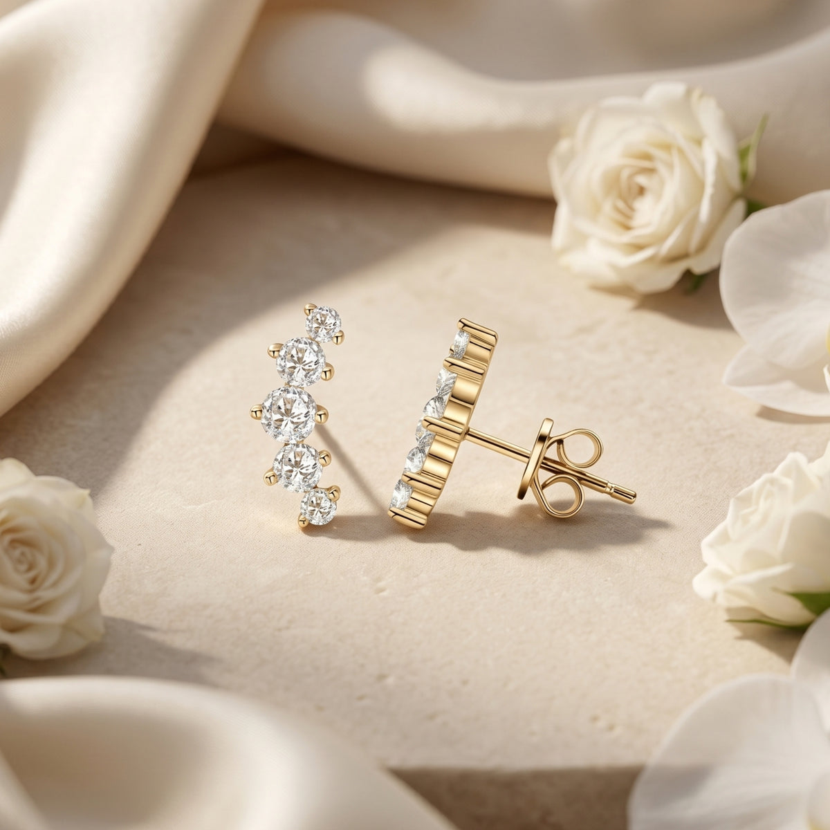 Pair of gold Valeriola moissanite climbers on stone surface with floral accents.